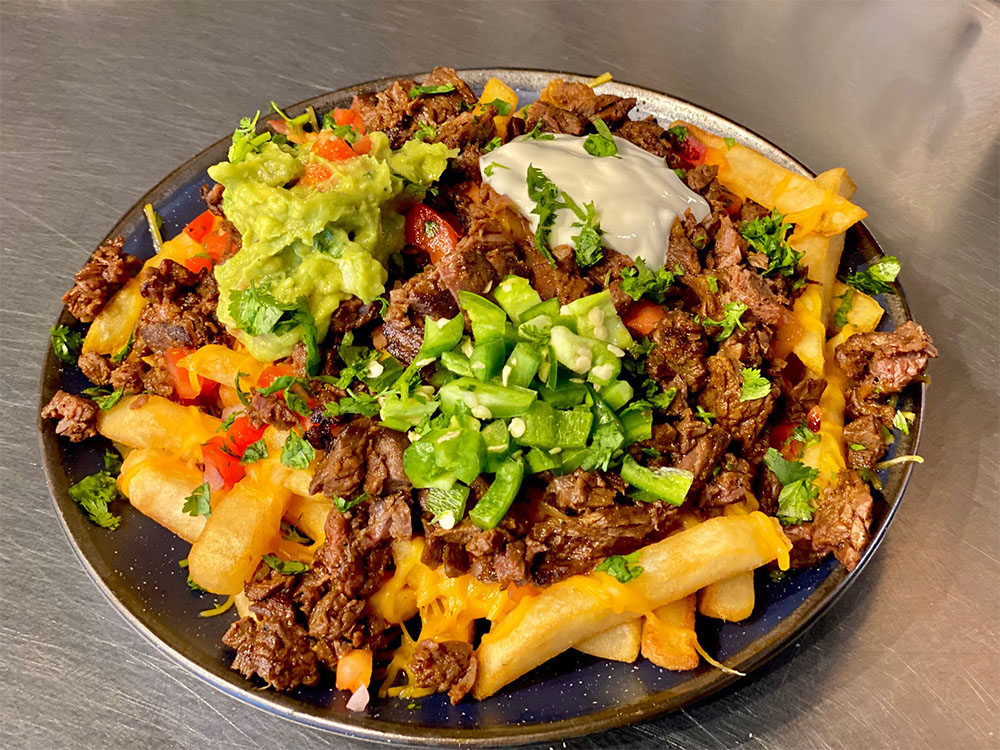 Loaded fries with guacamole, fresh jalapenos, tomatoes and crema